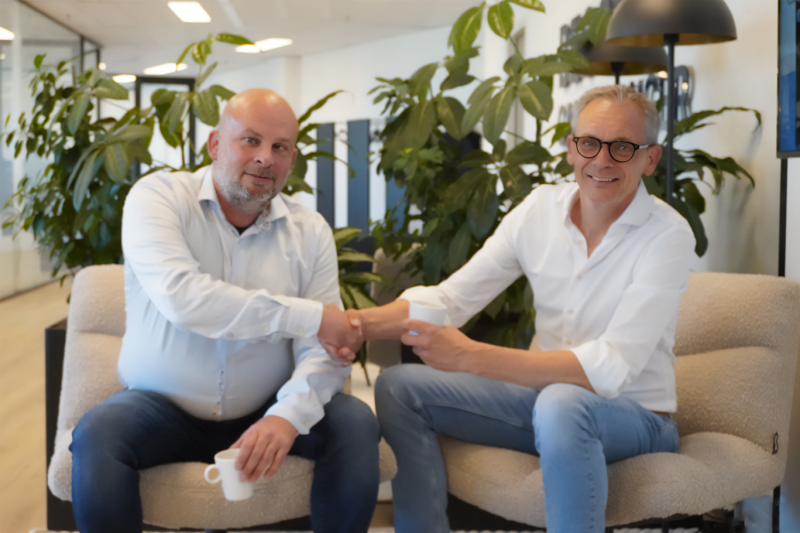 twee mannen schudden handen, zittend op stoelen.
