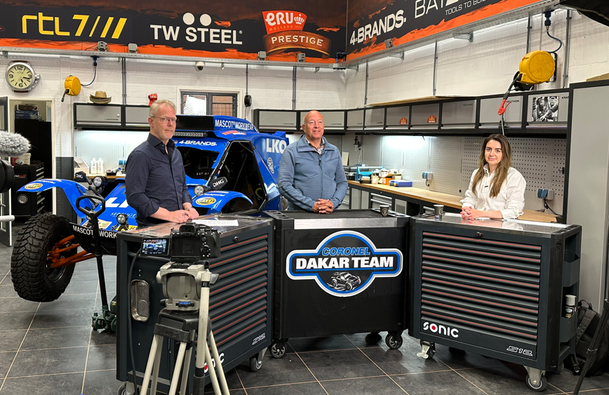 drie mensen bij dakar teamauto in garage-studio.