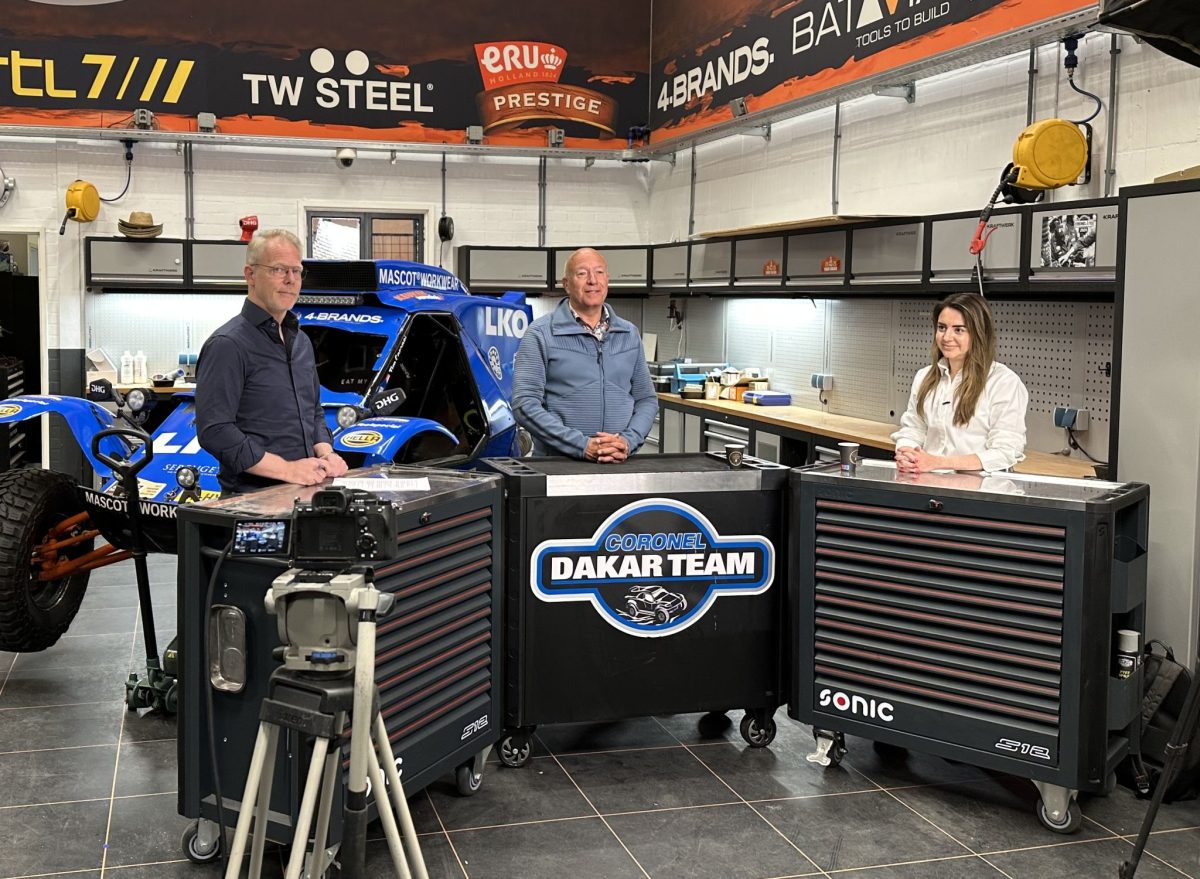 drie mensen bij dakar team met blauwe raceauto.